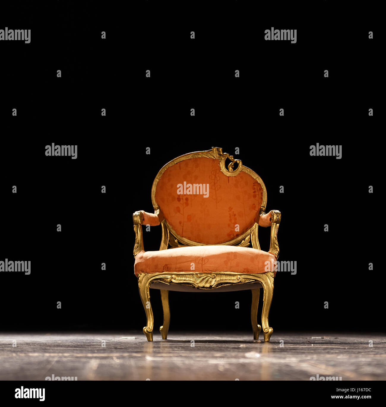 Vintage sedia arancione sul palcoscenico teatrale contro scuro dello sfondo nero Foto Stock