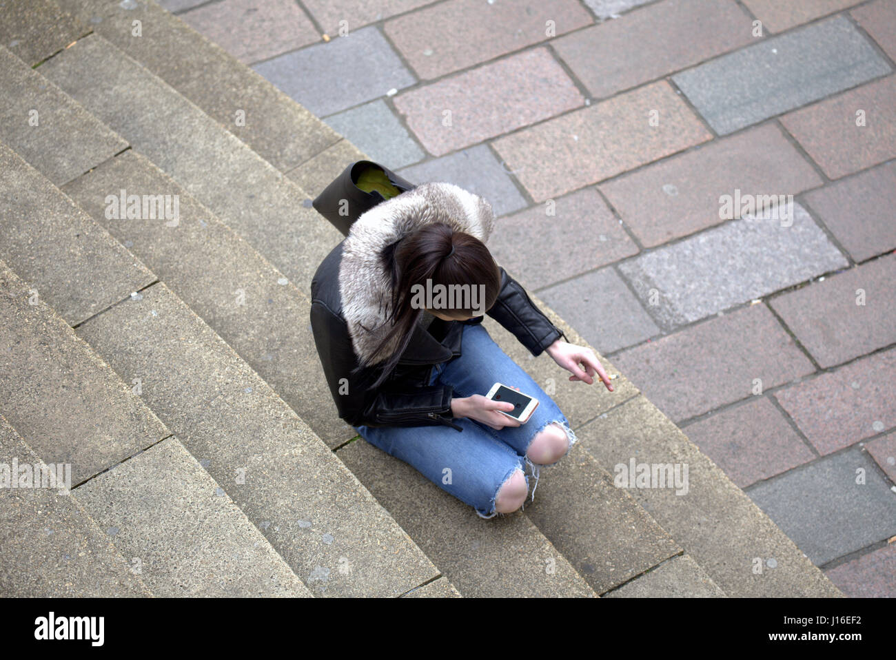 Ragazza giovane donna seduta anf di fumare mentre si utilizza il telefono cellulare Glasgow concert hall passi in corrispondenza della giunzione di Buchanan Street Sauchiehall Street Foto Stock