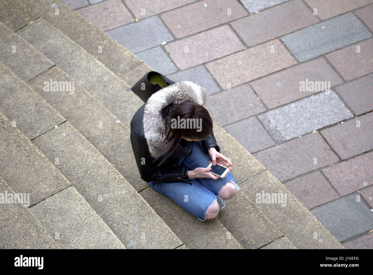 Ragazza giovane donna seduta anf di fumare mentre si utilizza il telefono cellulare Glasgow concert hall passi in corrispondenza della giunzione di Buchanan Street Sauchiehall Street Foto Stock