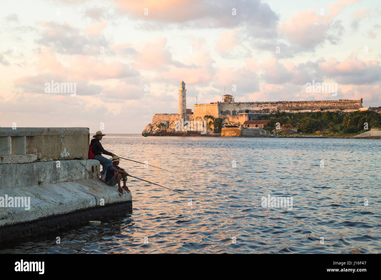 I pescatori cubano sul Malecon Seawall con il Castillo de los Tres Reyes del Morro in background Foto Stock