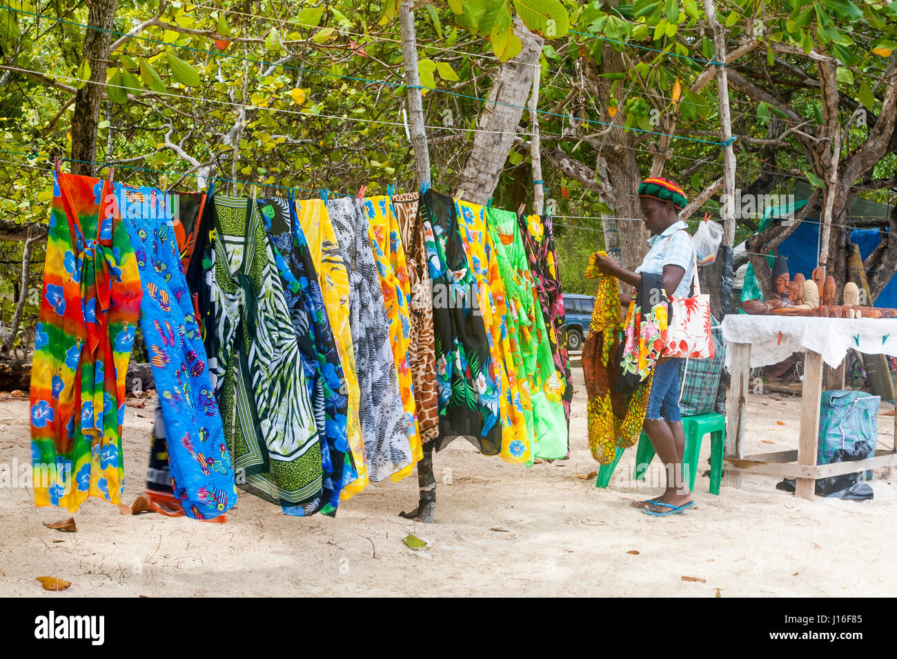 Ottenere pronto: a lato della spiaggia di vendita Display sarong, T-shirt e altri souvenir: Salt Whistle Bay, Mayreau, Saint Vincent e Grenadine. Foto Stock