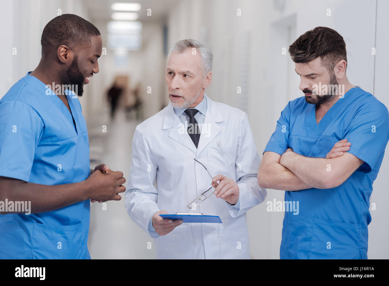 Strict invecchiato praticante consulting giovani colleghi in ospedale Foto Stock