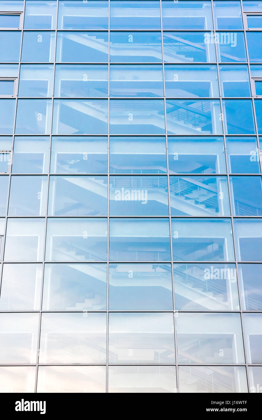 Moderno edificio di vetro esterno con scala dietro la facciata di vetro Foto Stock