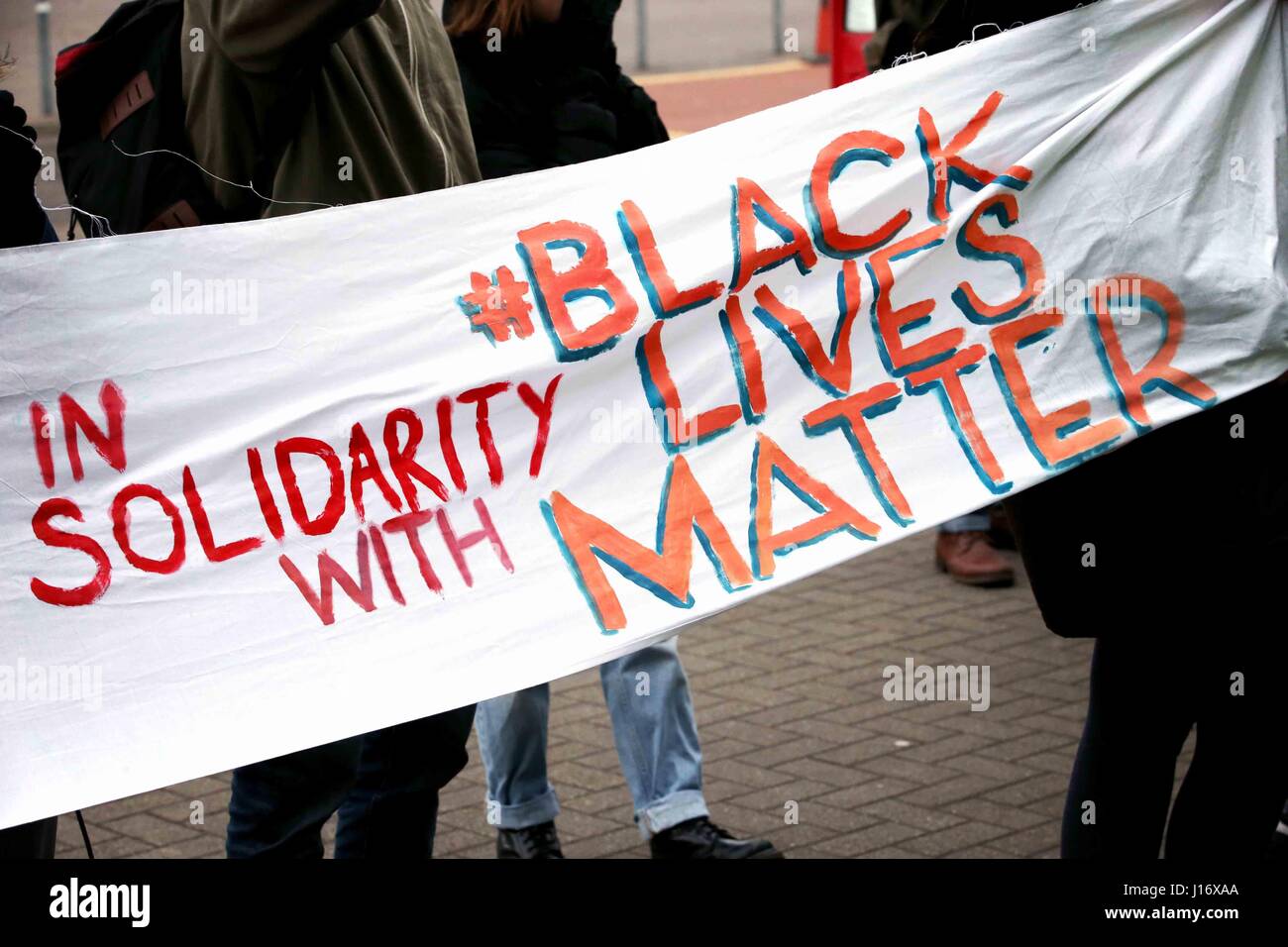 Le persone in attesa di un segno a leggere 'In solidarietà con nero vive questione'. Foto Stock