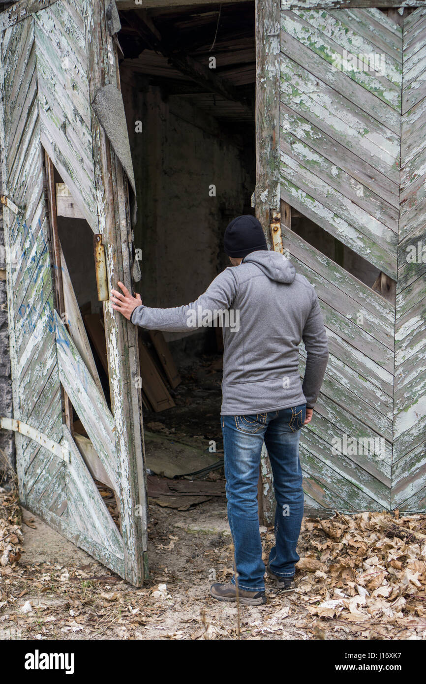 Vista posteriore di un uomo apertura deserta derlict barn Foto Stock