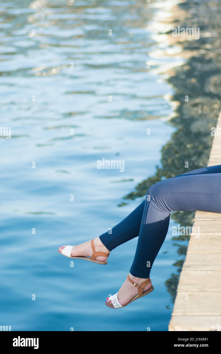In prossimità di una donna per le gambe seduto sul pontile sul mare Foto Stock