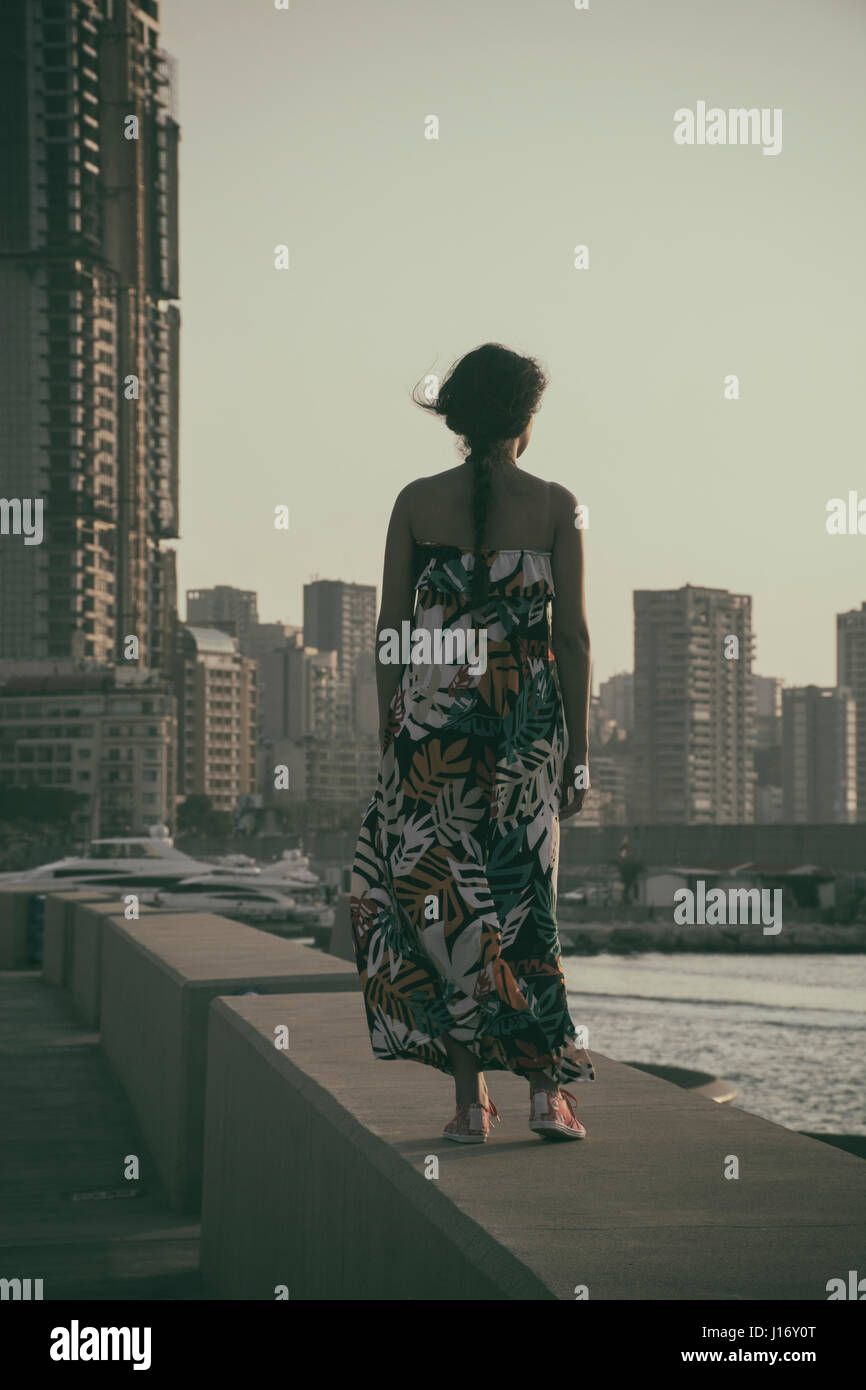 Vista posteriore di una donna che indossa un vestito estivo in piedi contro lo skyline Foto Stock