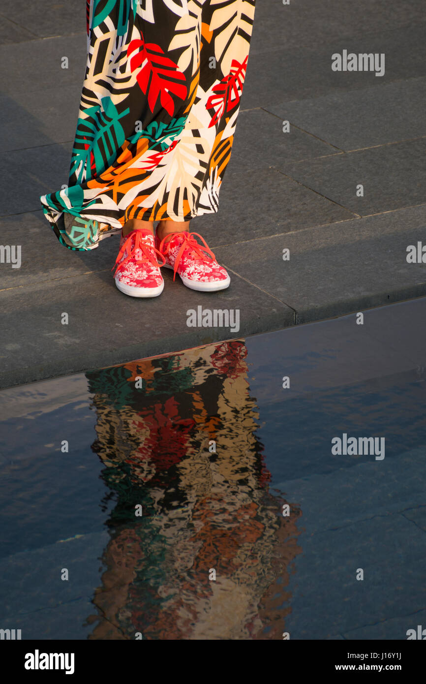 In prossimità di una donna che indossa i formatori e gli abiti estivi in piedi dalla funzione dell'acqua all'aperto Foto Stock