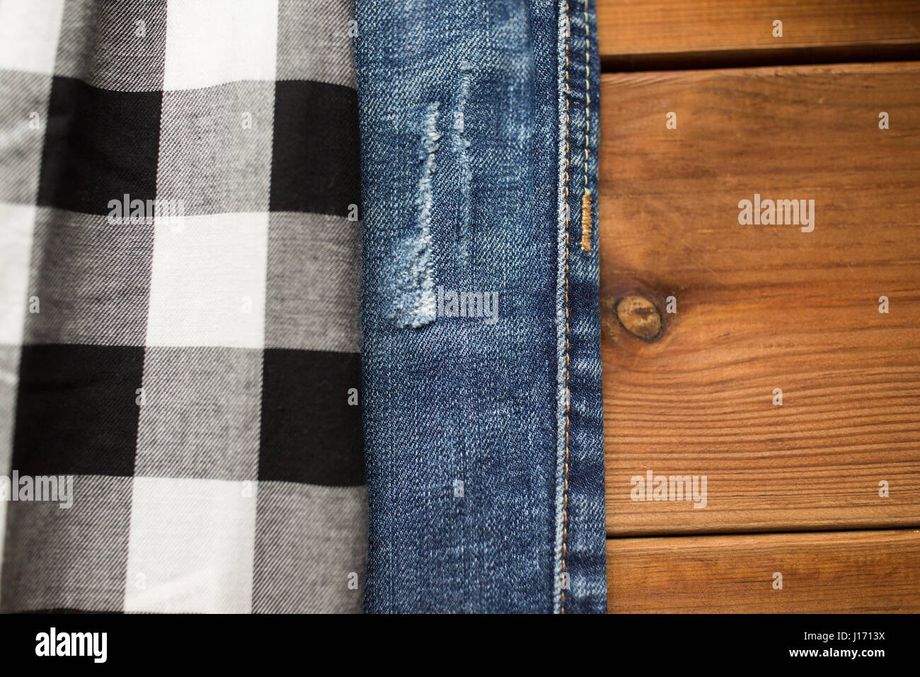 Ravvicinata di una camicia a scacchi e jeans su legno Foto Stock