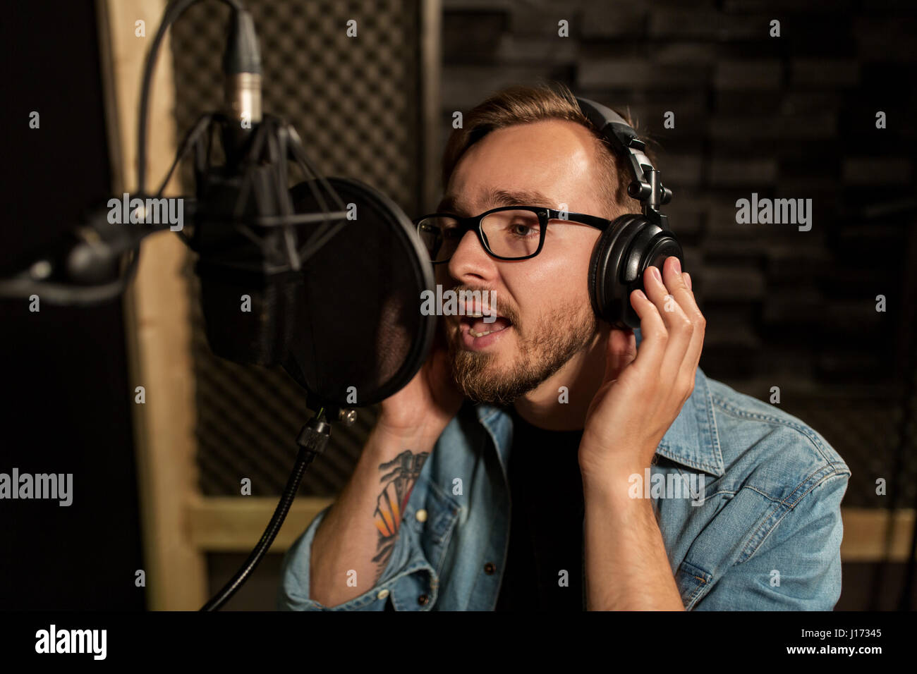 Uomo con cuffie cantando in studio di registrazione Foto Stock