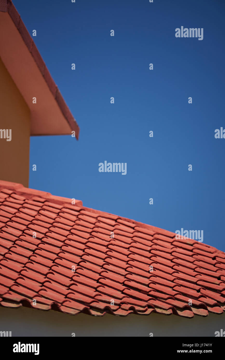 L'argilla rossa casa tegole del tetto sul cielo blu sullo sfondo Foto Stock