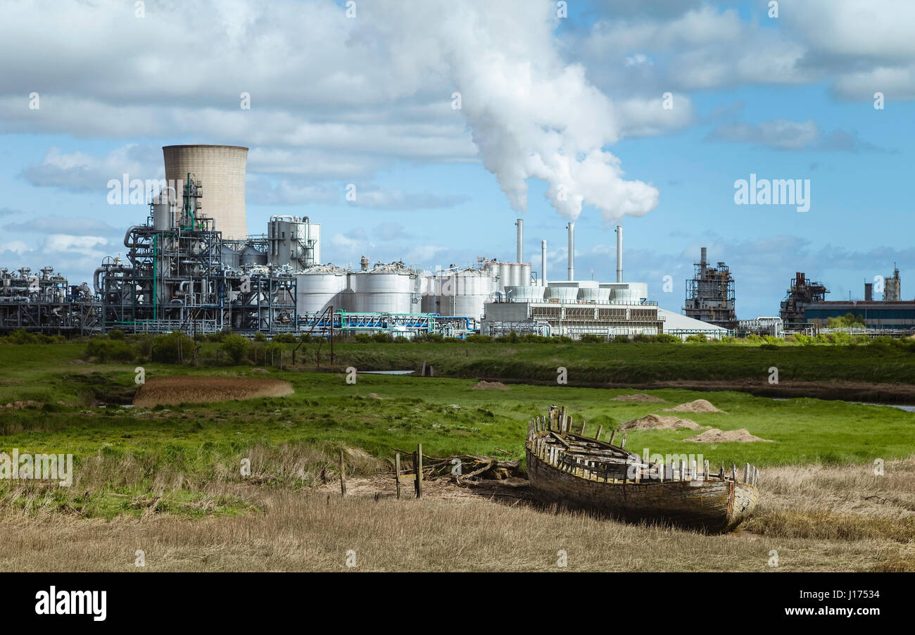 Una piccola abbandonati in barca in legno puntato su Troon Haven e sullo sfondo di un industria pesante con fumo muggito fuori su una luminosa mattina di primavera. Foto Stock