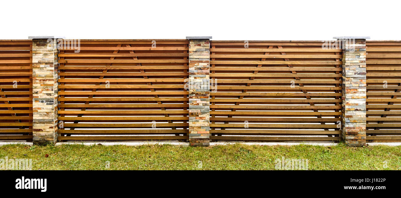 Giardino in legno con recinto lastricato in pietra pilastri proteggere la proprietà privata. Recinzione fatta orizzontali di tavole di legno e backyard prato. Foto Stock