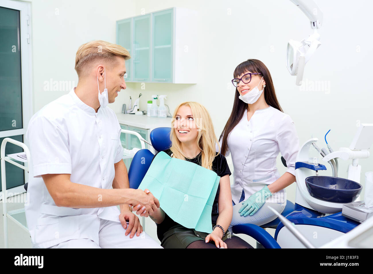 Il dentista scuote le mani con il paziente dopo il trattamento dentale Foto Stock