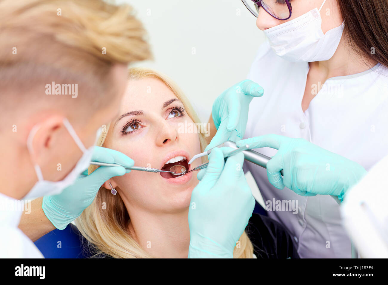 Due dentisti trattare i loro denti al visitatore in studio dentistico Foto Stock