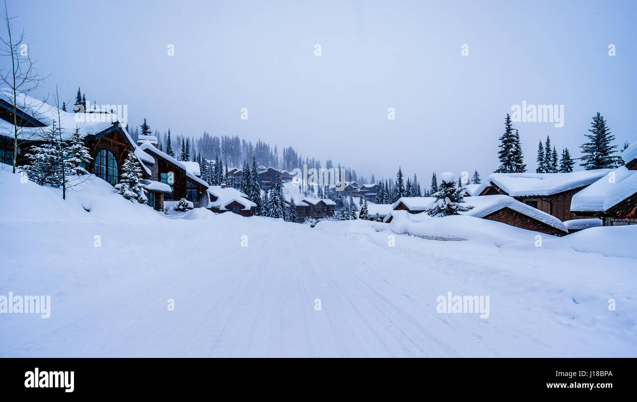 Una scena di strada con una coperta di neve e su strada coperta di neve tetti nel villaggio alpino in British Columbia, Canada Foto Stock