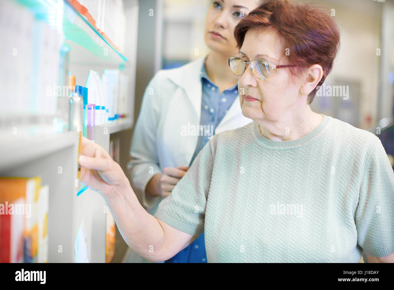 Il farmacista aiutando donna senior con obbligo di ricetta Foto Stock