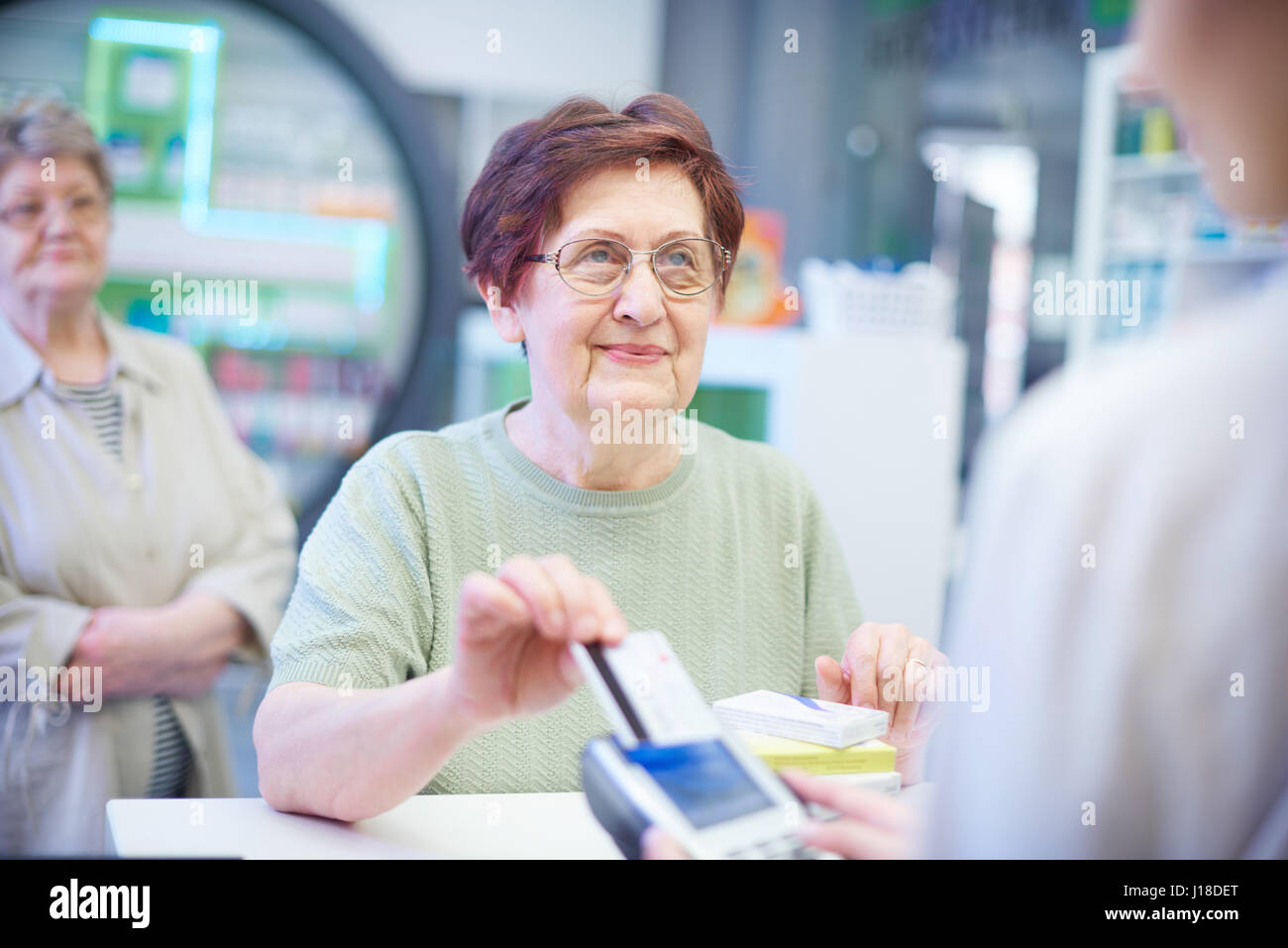 Senior donna pagando con carta di credito in farmacia Foto Stock