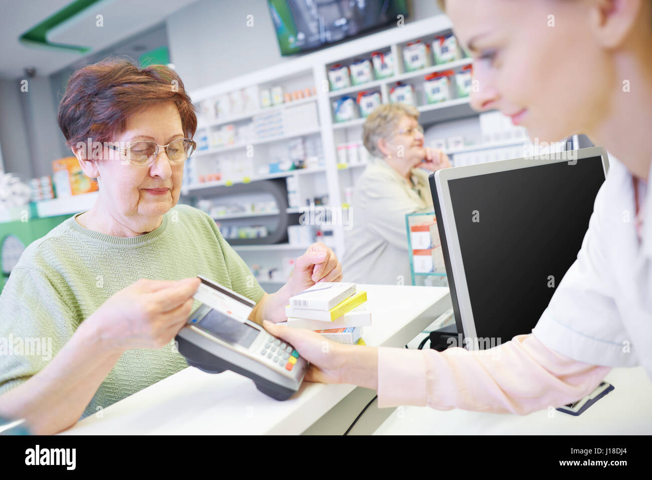 Il cliente di pagare mediante carta di credito presso un negozio di droghe Foto Stock