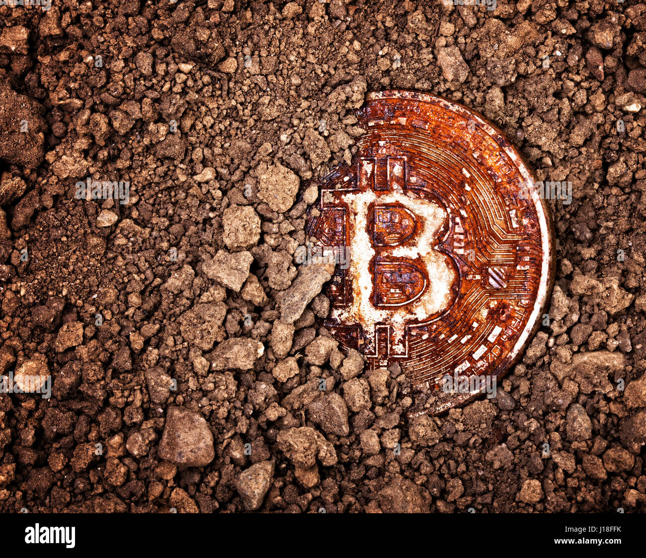 Primo piano su rusty bitcoin sepolto in un terreno il concetto di obsolescenza Foto Stock