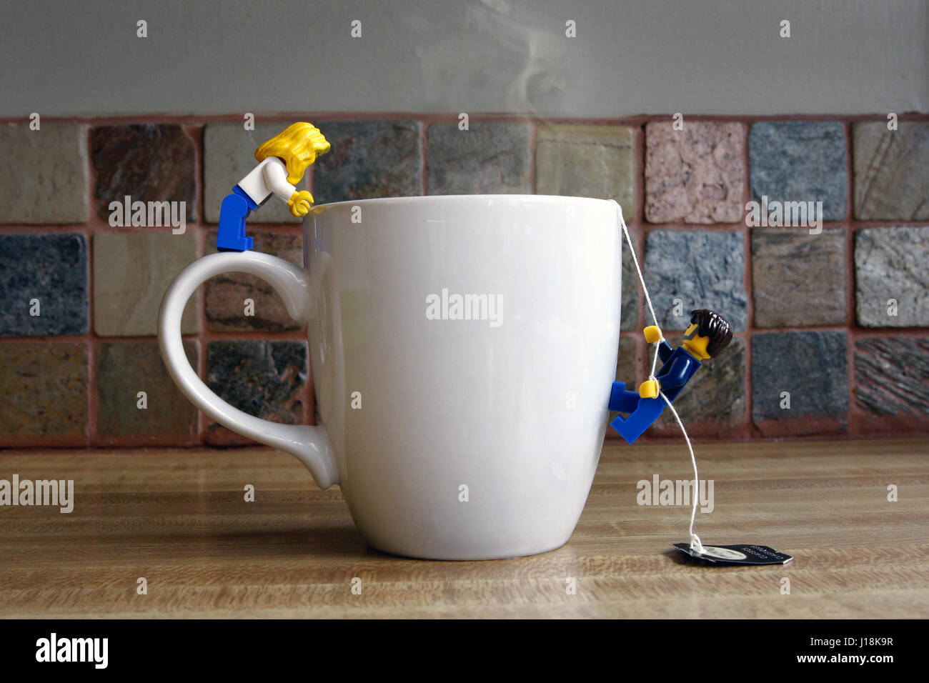 Maschio e femmina gente lego arrampicata in una tazza di tè Foto