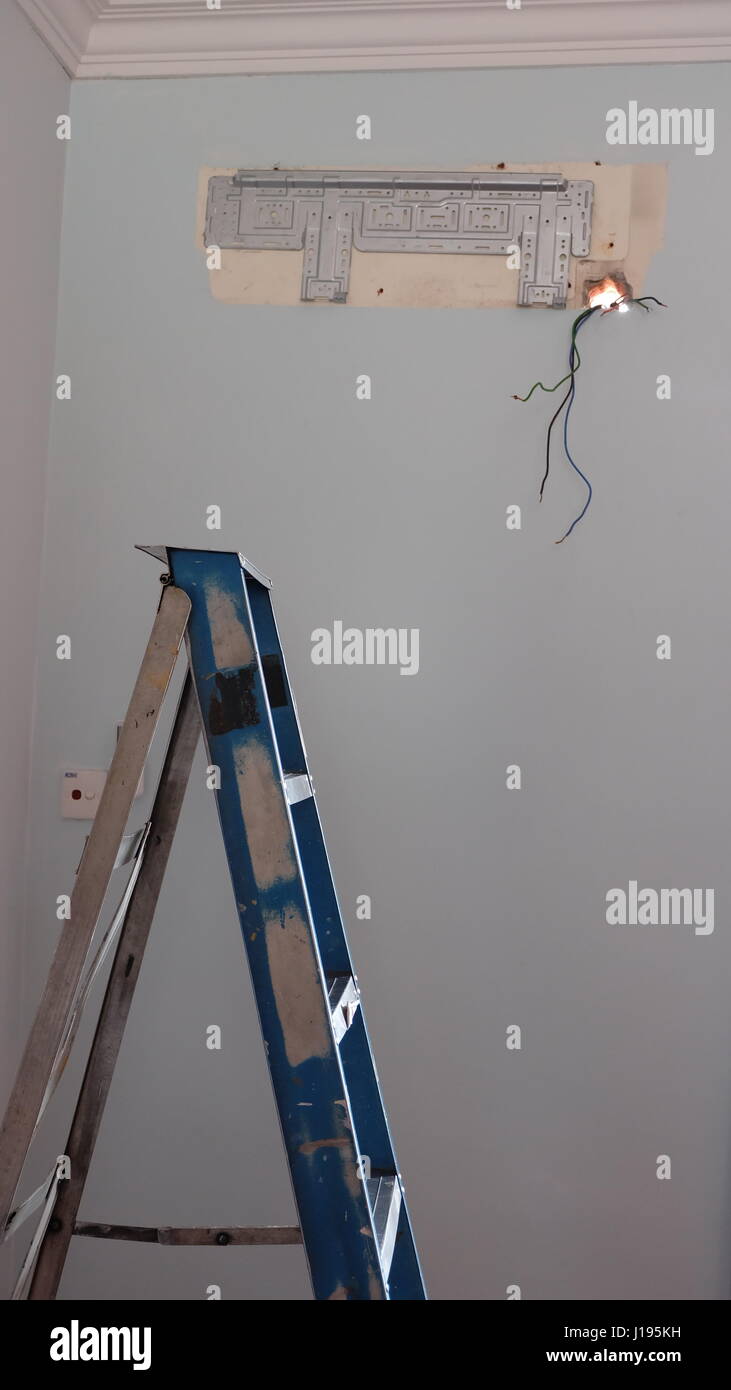 Scaletta vicino a una parete con il contrassegno o traccia di un condizionatore smontati Foto Stock
