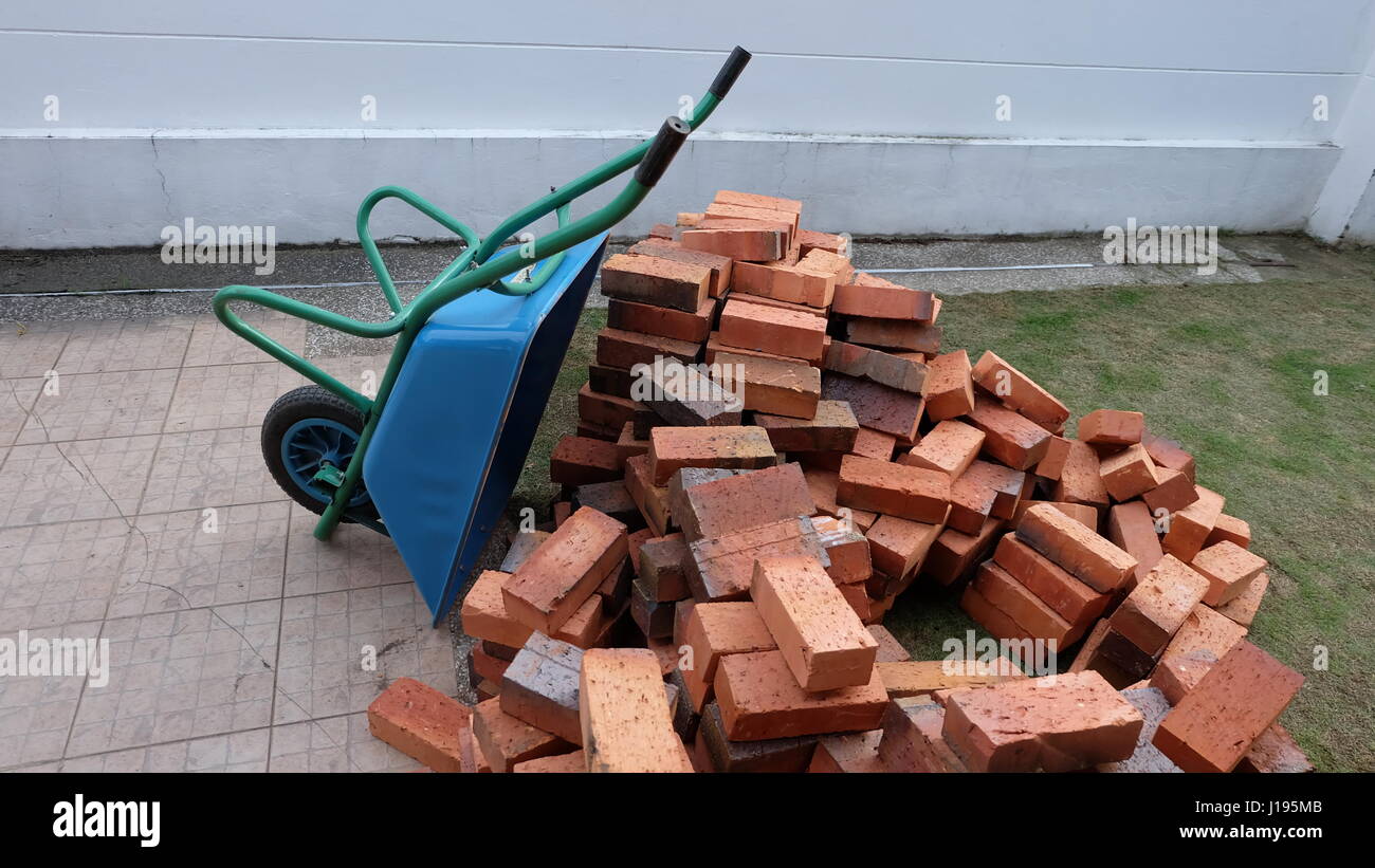 Un mucchio di mattoni con blue carriola o carrello di costruzione Foto Stock