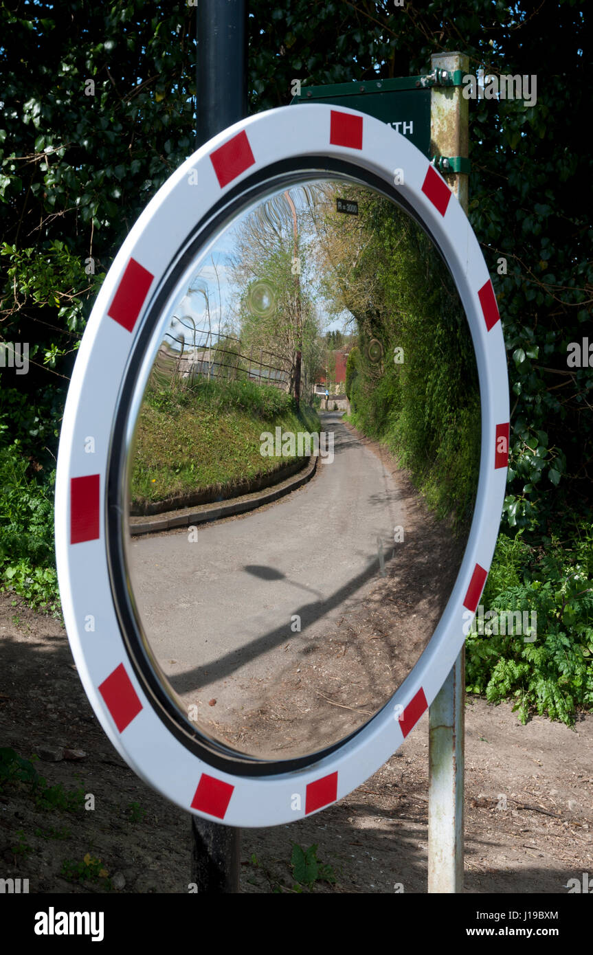 Una superficie convessa la sicurezza stradale specchio nel centro del villaggio di Barton, Oxfordshire, England, Regno Unito Foto Stock