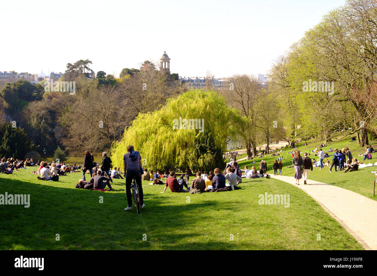 Le persone che si godono il sole di primavera nel parco Buttes-Chaumont, Parigi, Francia Foto Stock