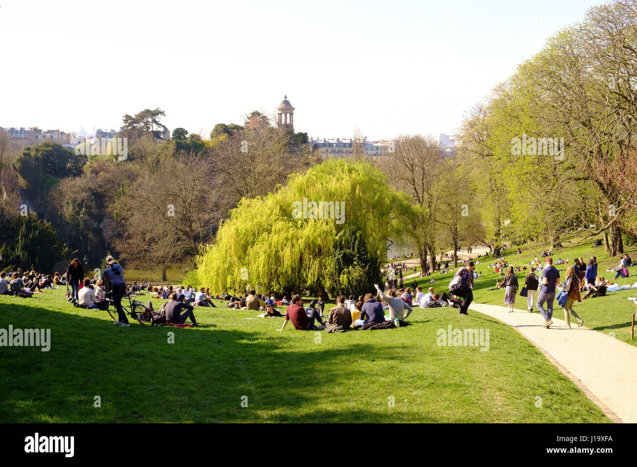 Le persone che si godono il sole di primavera nel parco Buttes-Chaumont, Parigi, Francia Foto Stock