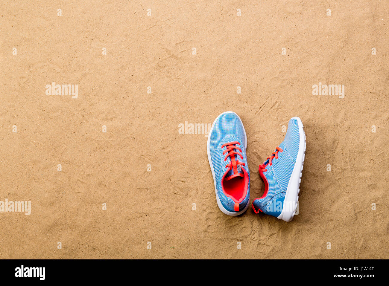 Blue sport scarpe con lacci delle scarpe rosa prevista sulla spiaggia di sabbia di sfondo, studio shot, piatto laici. Copia dello spazio. Foto Stock