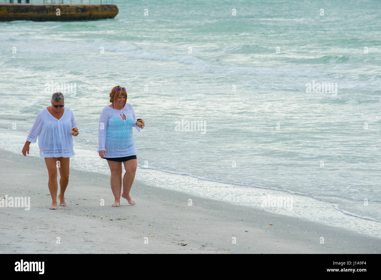 La gente sulla spiaggia alla ricerca di conchiglie di mare Foto Stock