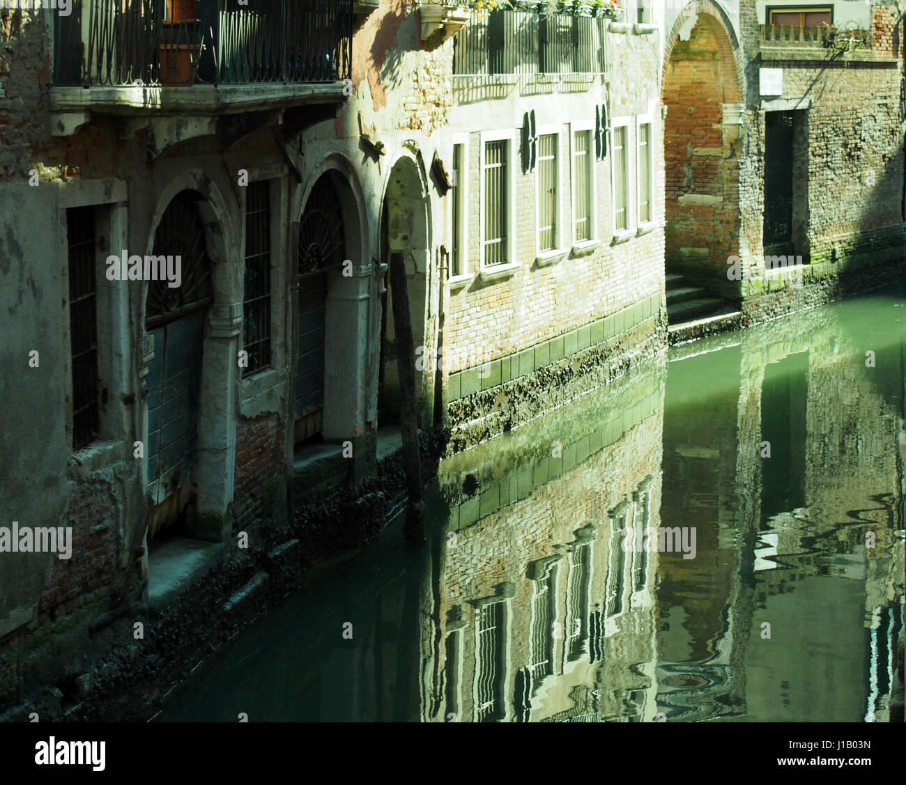 Canale di Venezia con riflessioni di edifici antichi muri di porte e finestre Foto Stock