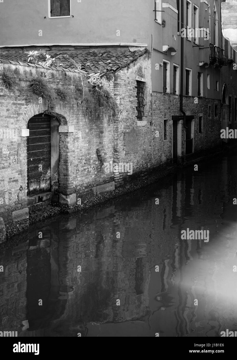 Canale di Venezia con riflessioni di edifici antichi muri di porte e finestre Foto Stock