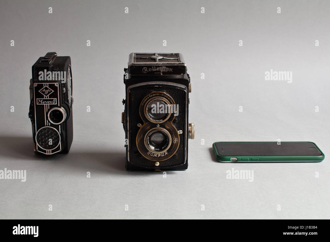 Più di due in uno. Smartphone è più di telecamere. Antique telecamera analogica. Ottica e strumenti meccanici - attrezzature fotografiche. Foto Stock