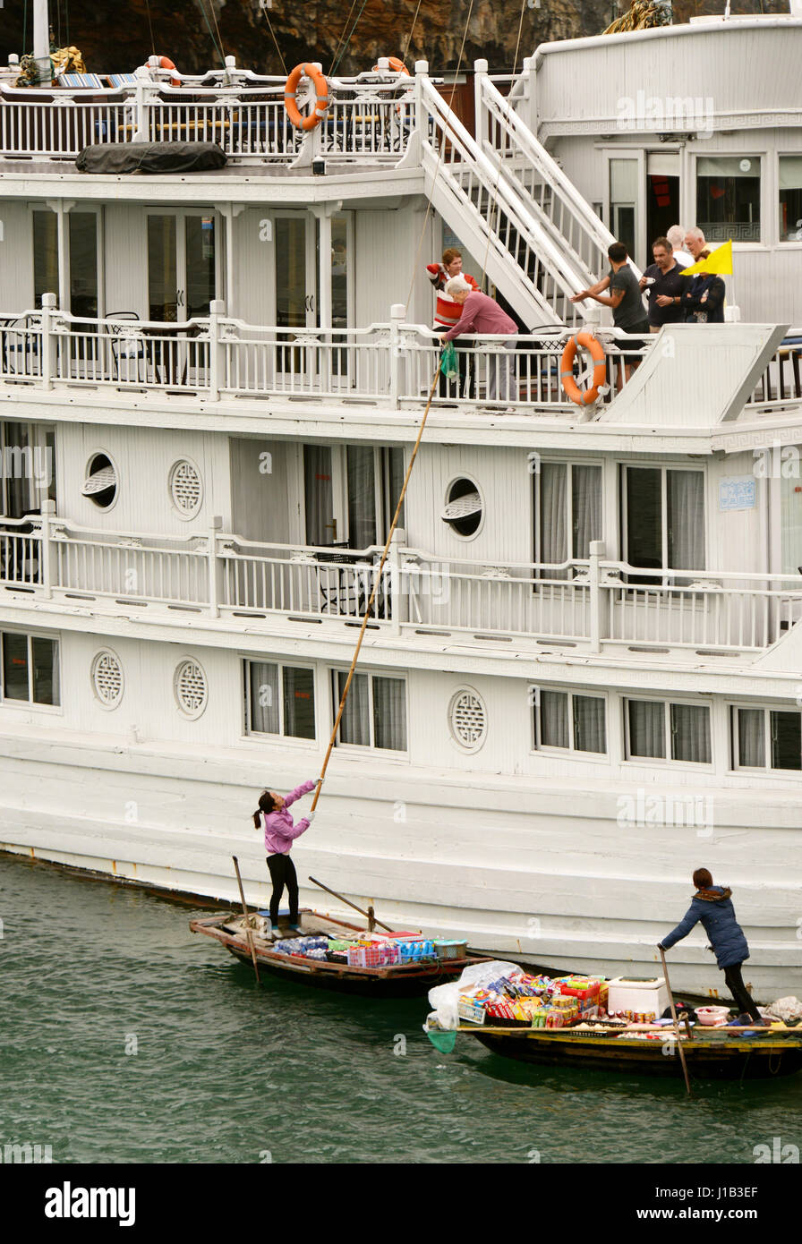 Fisherman's famiglie nella baia di Halong contribuire al reddito familiare con la vendita di spuntini e negozio di souvenir al passaggio di imbarcazioni turistiche. Foto Stock