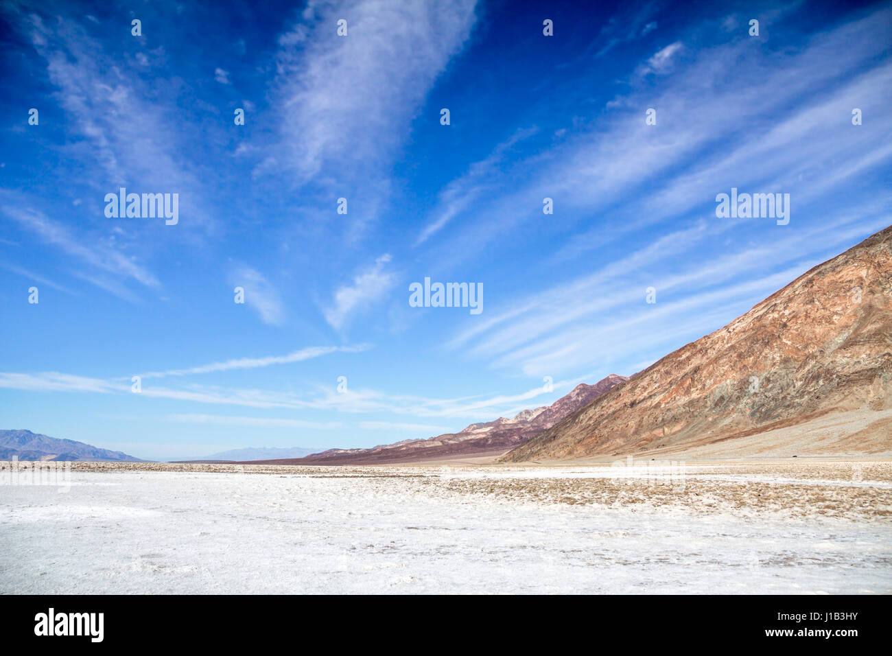 Saltflats del bacino Badwater, Parco Nazionale della Valle della Morte, CA. Sotto un profondo cielo blu, radiante cirrus nuvole portano l'occhio a distanza Foto Stock