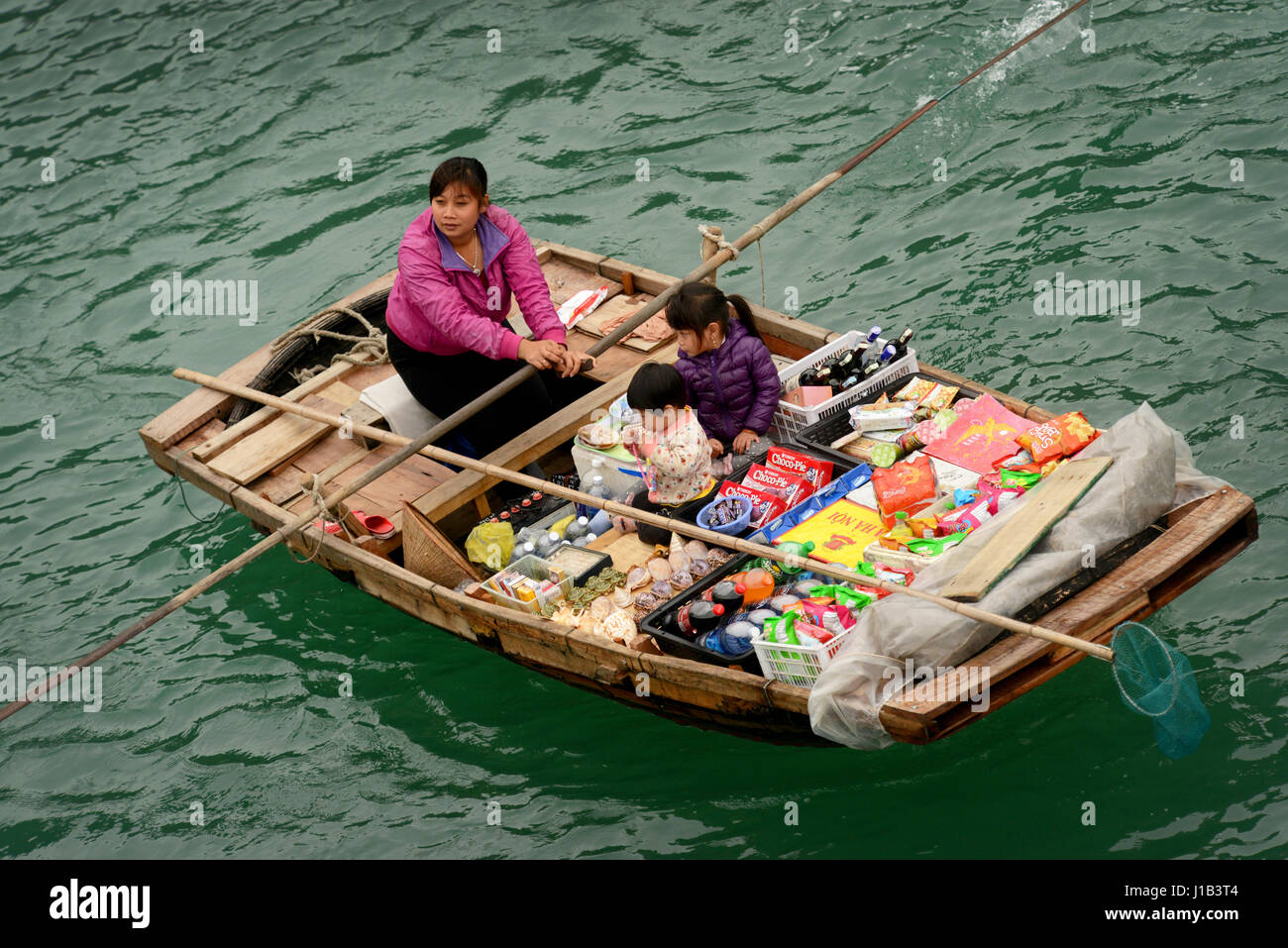 Fisherman's famiglie nella baia di Halong contribuire al reddito familiare con la vendita di spuntini e negozio di souvenir al passaggio di imbarcazioni turistiche. Foto Stock