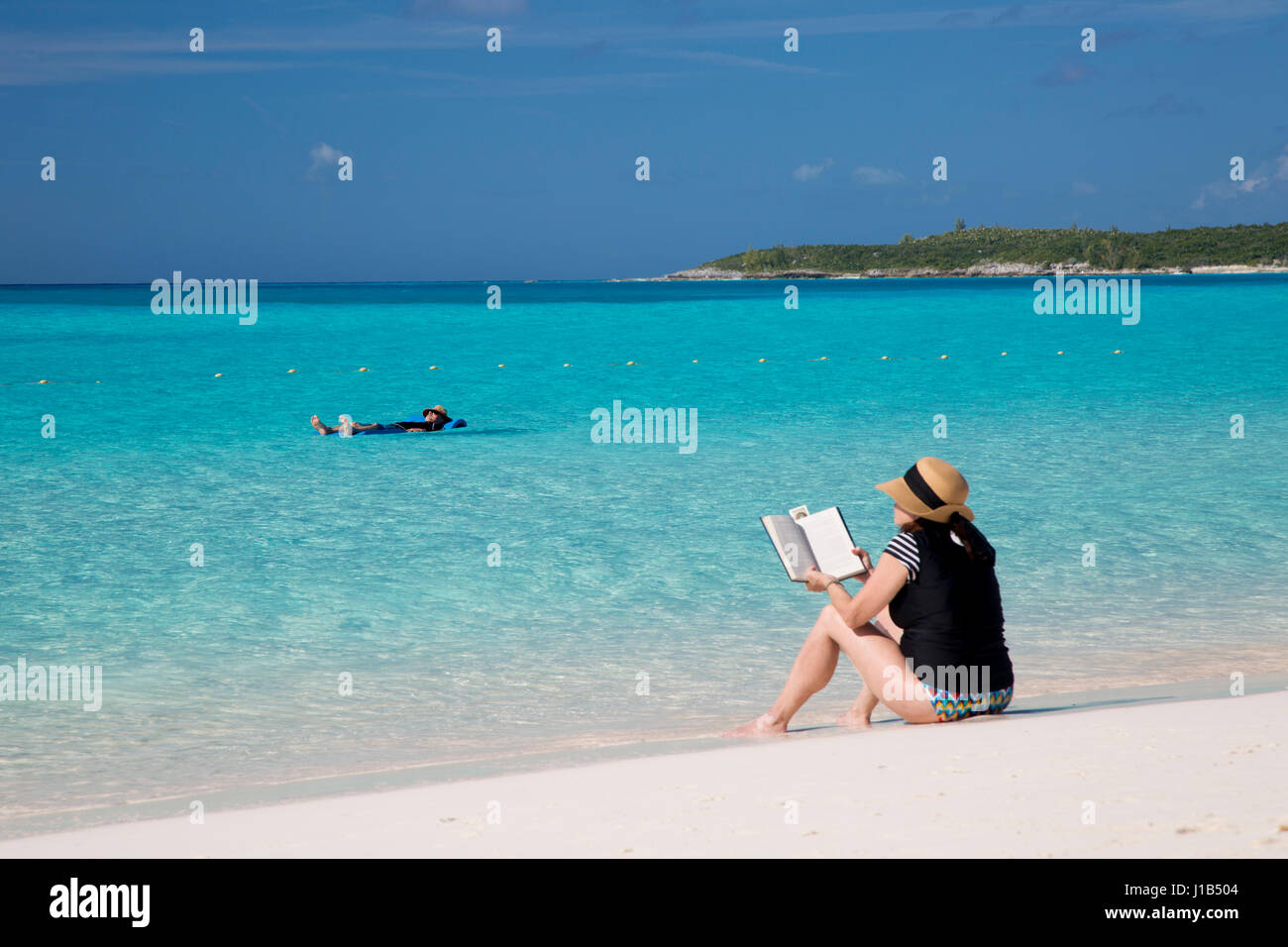 Donna libro di lettura sulla spiaggia, Halfmoon Cay, Bahamas Foto Stock