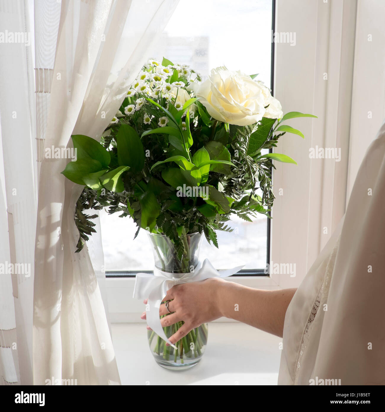 La donna caucasica immissione vaso di fiori sul davanzale della finestra Foto Stock