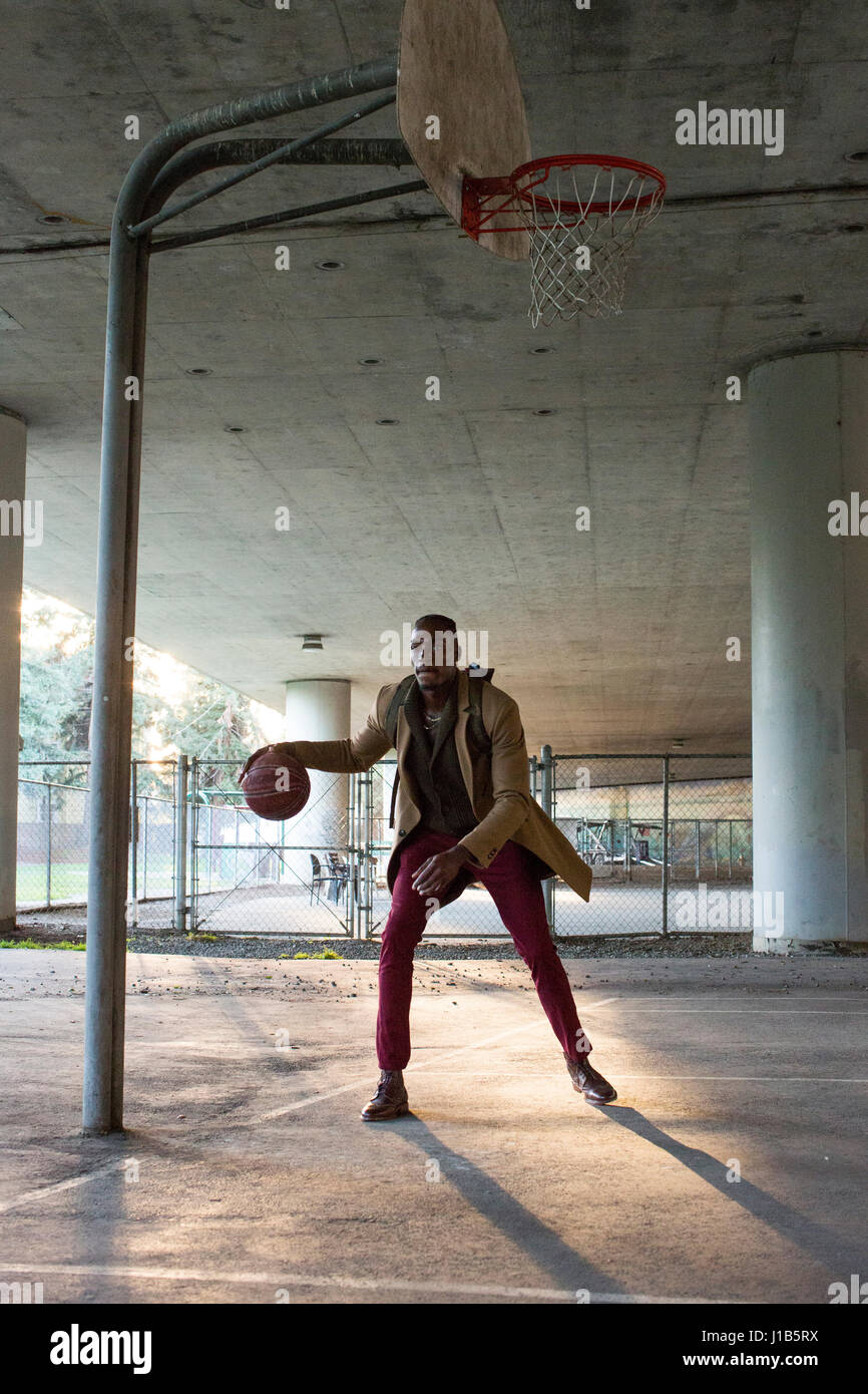 Uomo nero indossando uno zaino giocare a basket sotto il cavalcavia Foto Stock