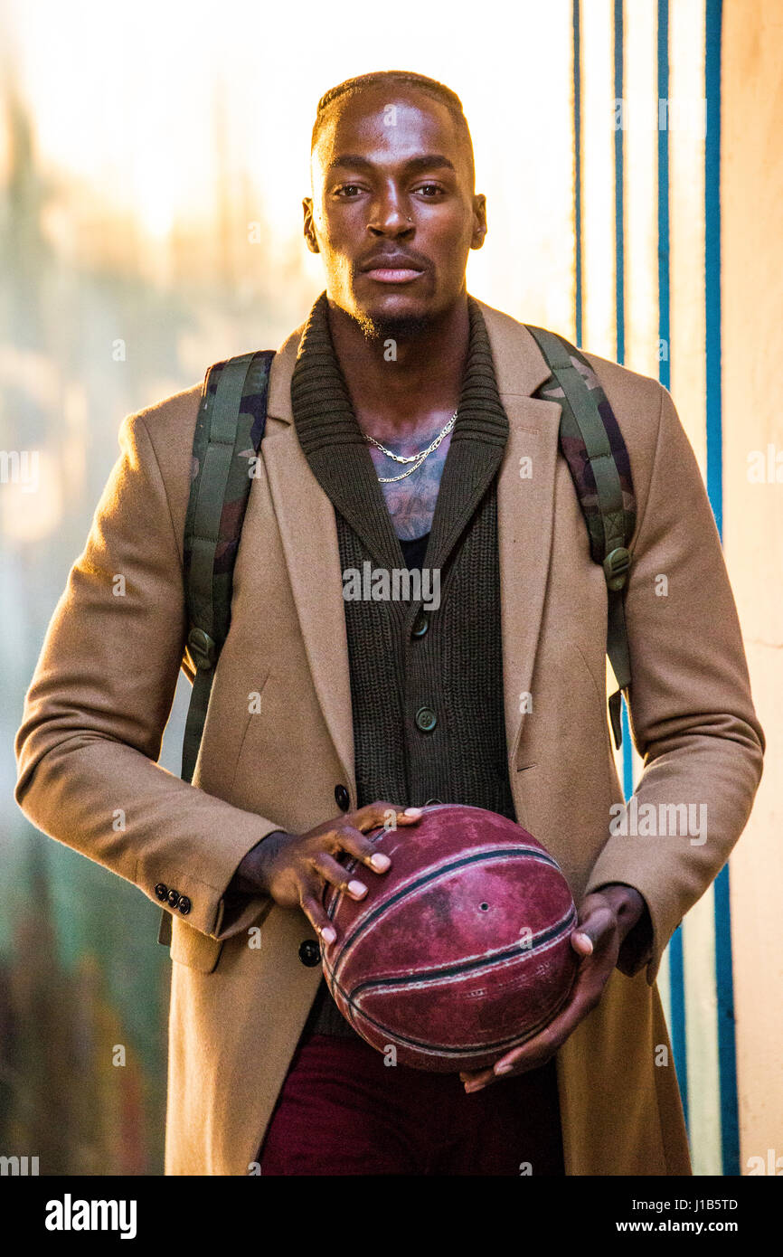 Uomo nero indossando uno zaino tenendo la pallacanestro Foto Stock