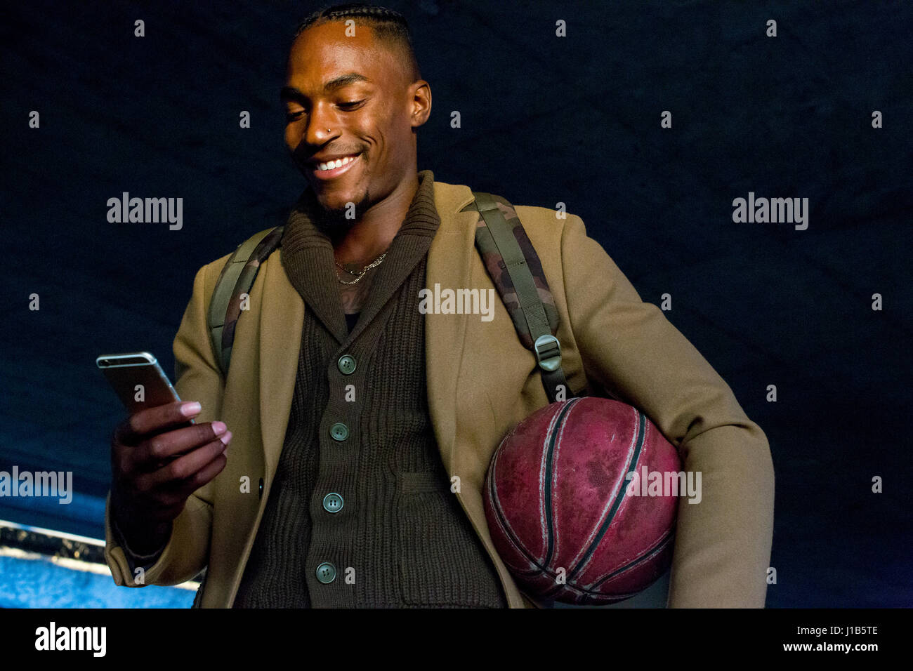 Uomo nero holding basket sms sul cellulare Foto Stock