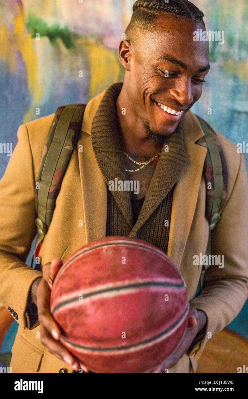Ridendo uomo nero indossando uno zaino tenendo la pallacanestro Foto Stock