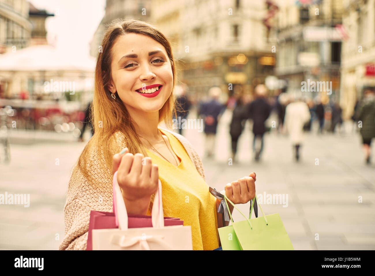 Una giovane donna felice con shopping bag in strada. Cinematic filtro tonificante. Foto Stock