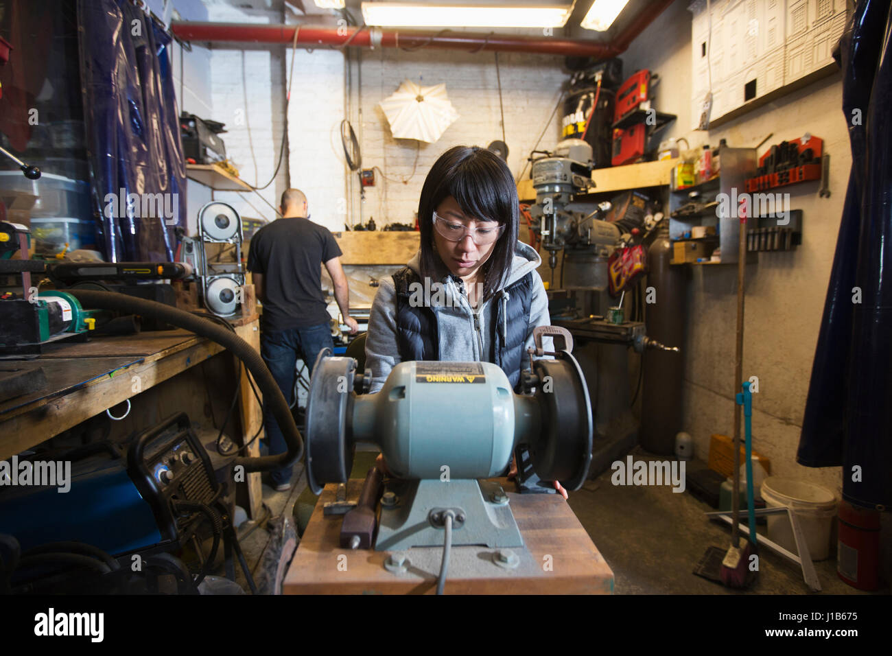 L uomo e la donna utilizzando macchinari in officina Foto Stock