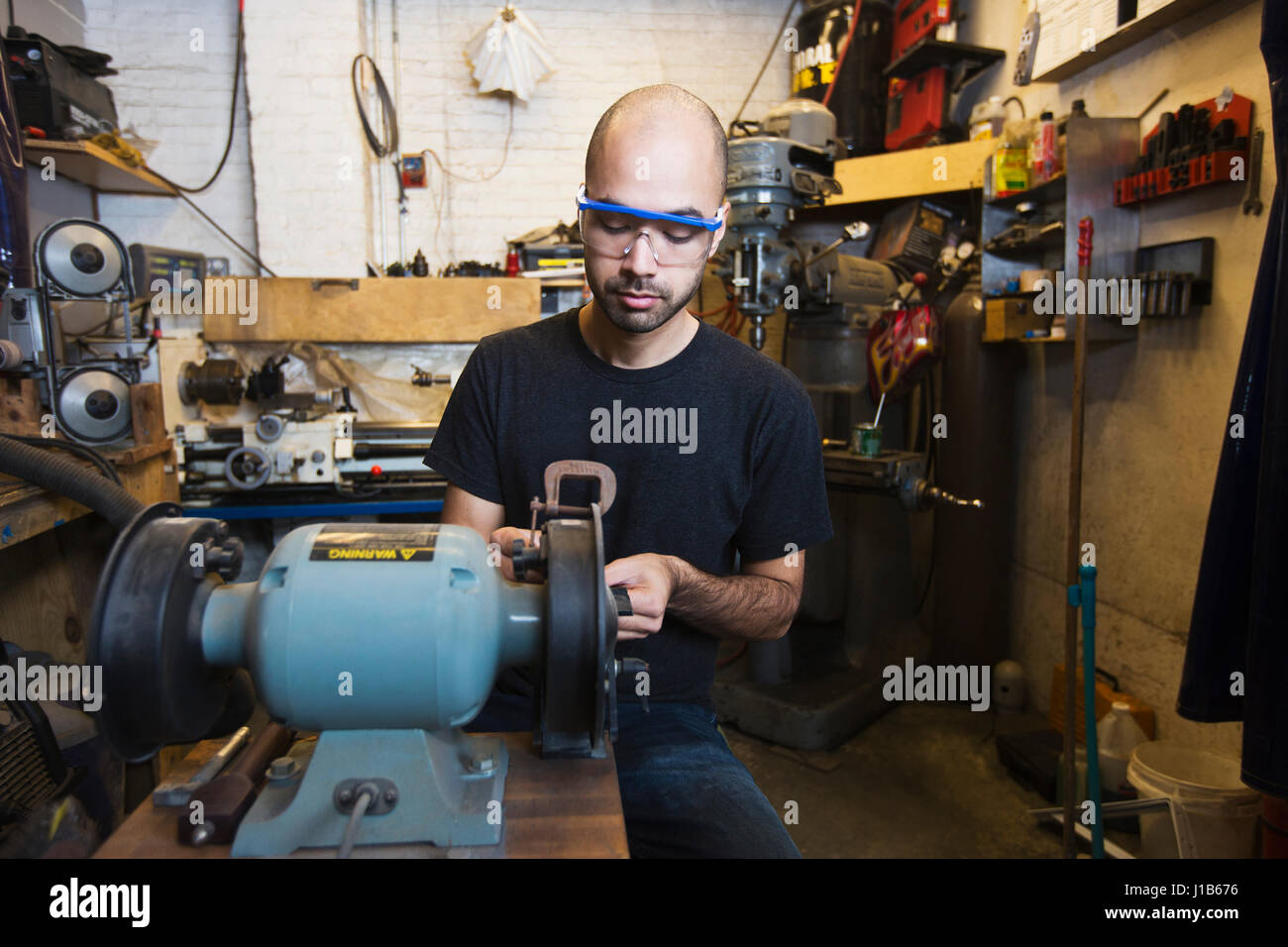 Razza mista uomo utilizzando macchinari in officina Foto Stock