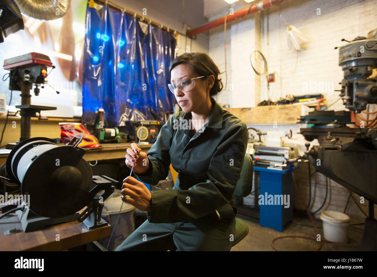 Razza mista donna azienda asta metallica in officina Foto Stock