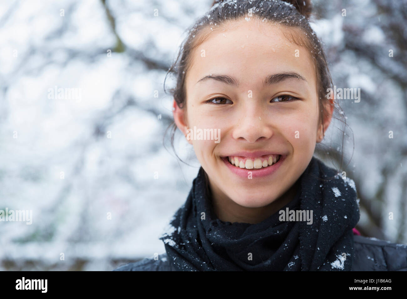 Sorridente razza mista ragazza ricoperta di neve Foto Stock