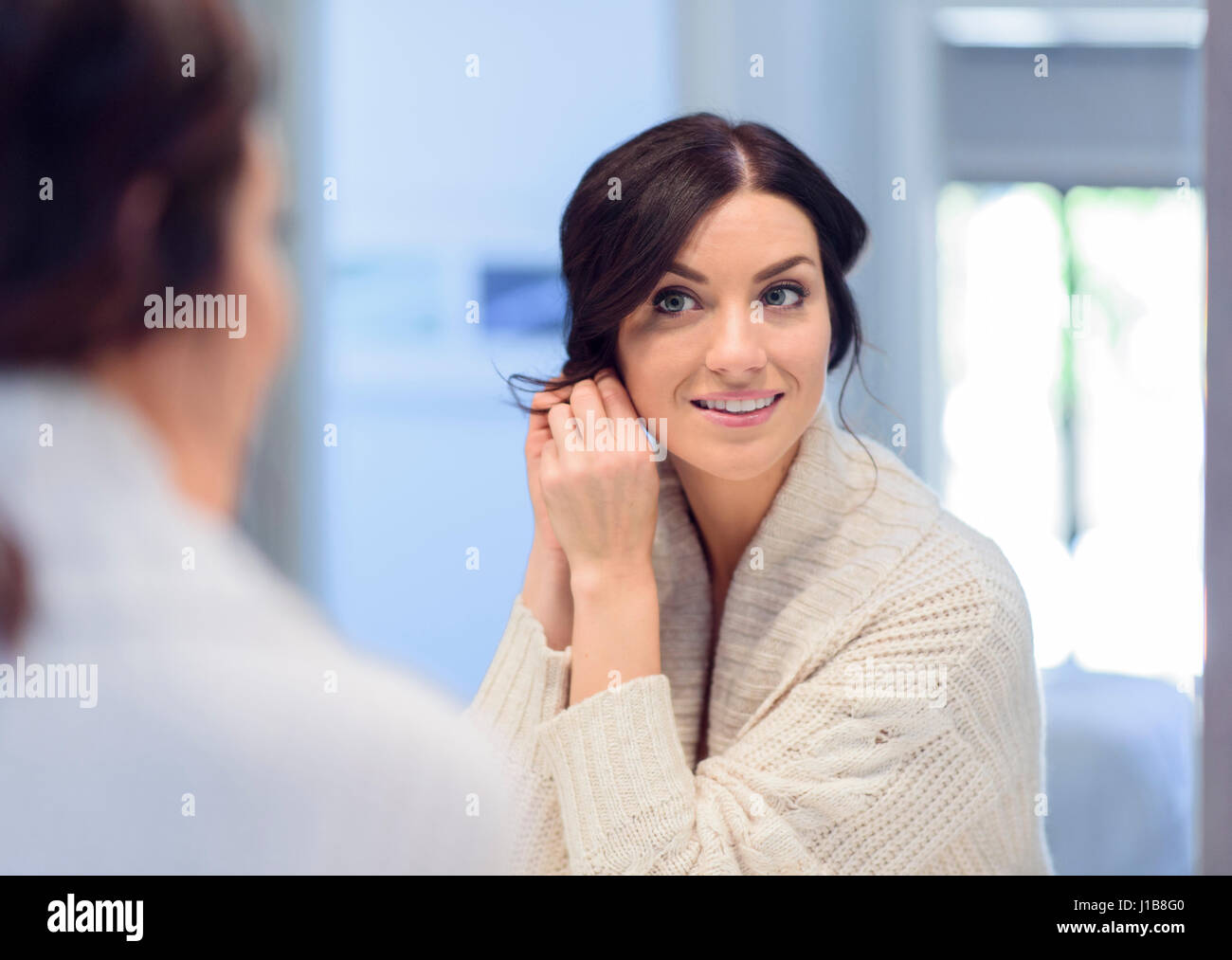 La donna caucasica orecchino di fissaggio dello specchio Foto Stock